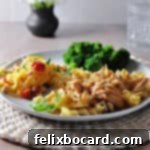 Instant pot french onion chicken with noodles on a plate with broccoli and a salad